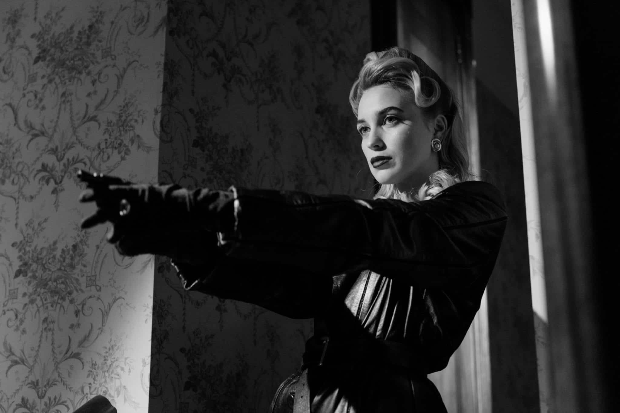 A woman pointing a gun in a black and white image.