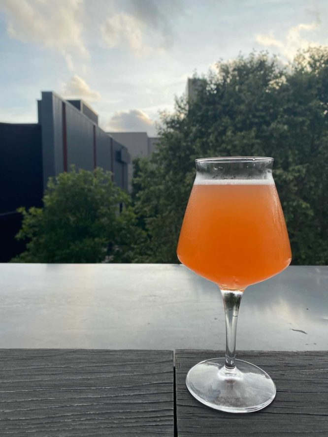 A photo of an orange glass of beer on a rooftop