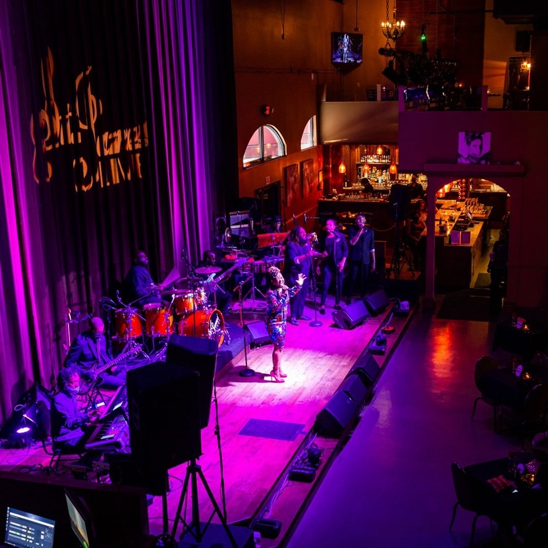 A jazz band performing on a stage illuminated by purple lighting.