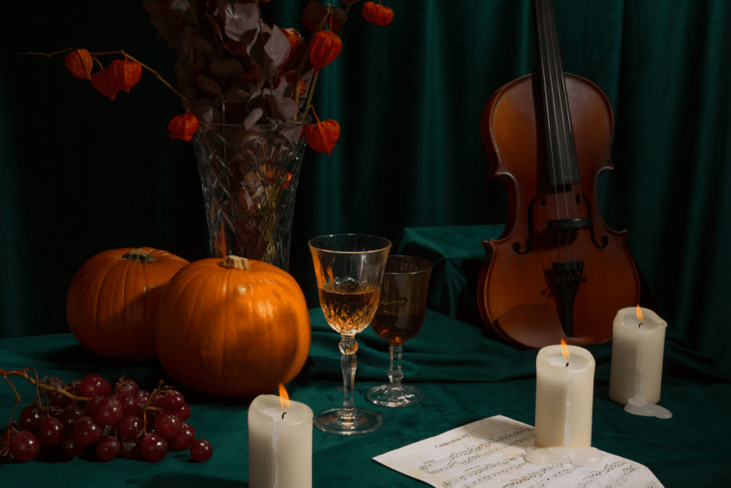 A table set up for Halloween with pumpkins candles and a violin.