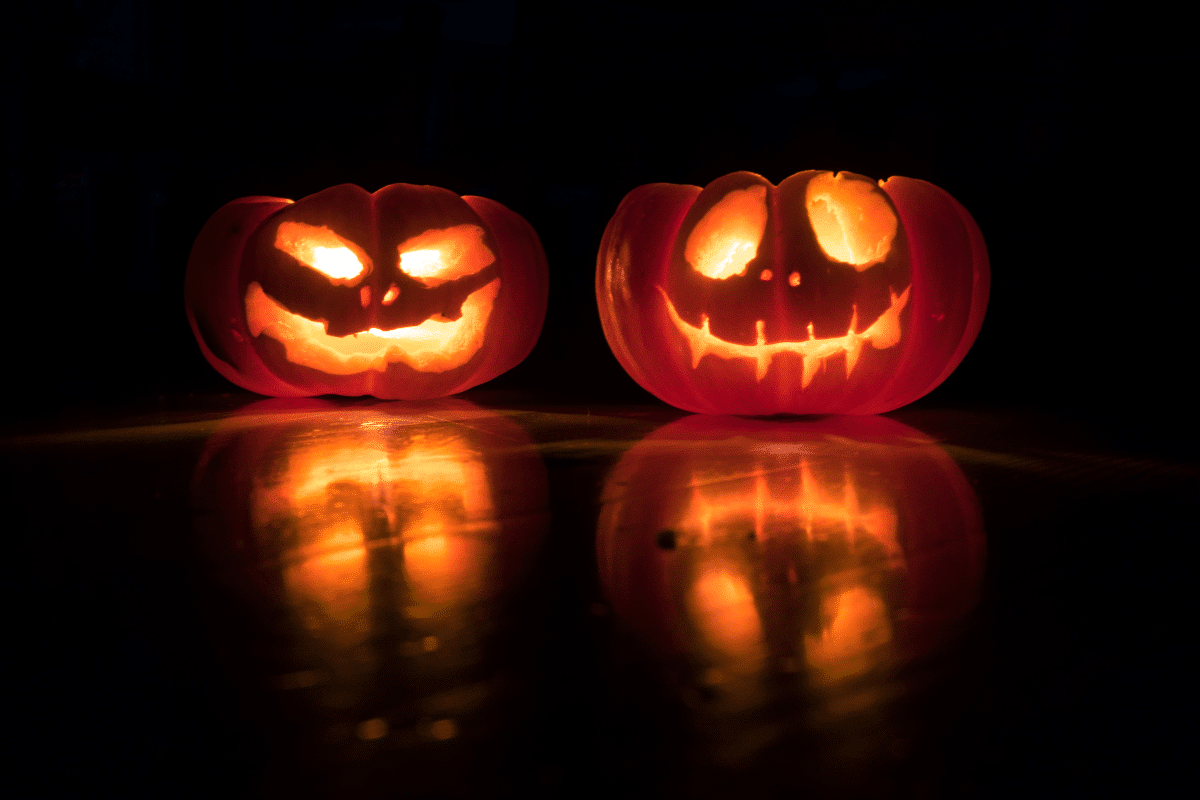 A close up of two pumpkins glowing in the dark.