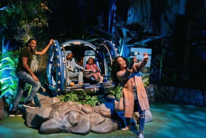 Image of a family enjoying the jurassic world exhibit in a large glass container, rolling through rocks