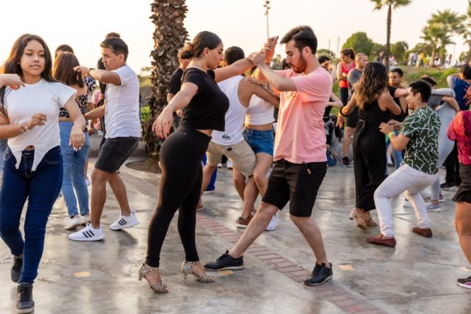 A group of people learning the dance the salsa in regular clothes