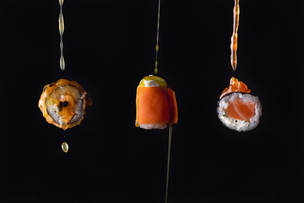 Three pieces of sushi suspended in the air with a black background.