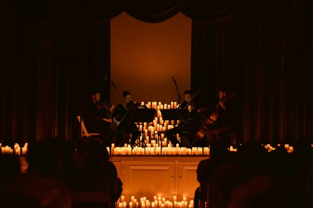 A string quartet performing on a stage surrounded by candles at one of Fever's Candlelight Concerts