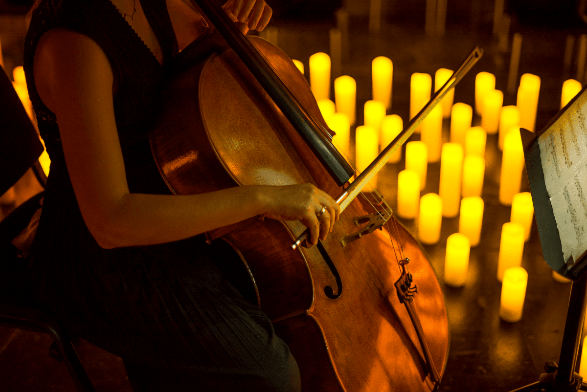 A close up of someone playing the cello by candlelight.