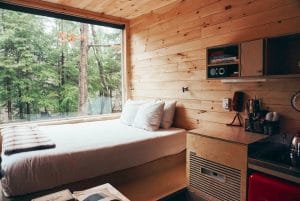 Tiny cabin view with queen sized bed and view of forest