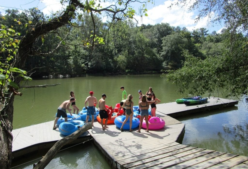 A group of people on a dock preparing to go river tubing.