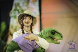 A woman holds a small dinosaur puppet