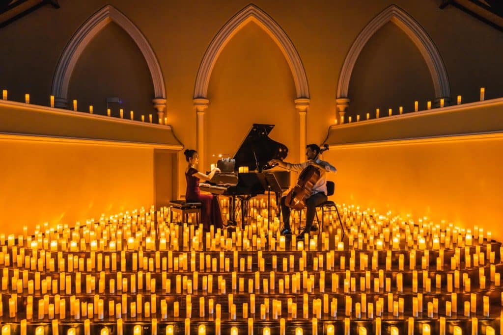 pianist and cellist surrounded by candles for candlelight live music performance