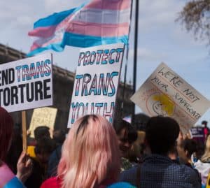 Signs and people rallying at a protest protecting trans lives