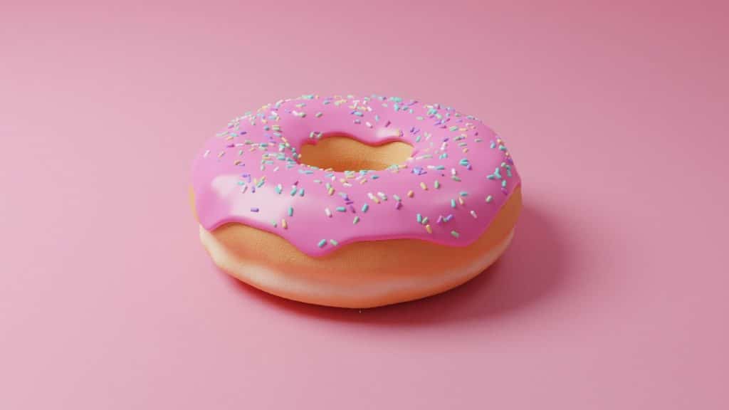 A pink. glazed donut on a pink background.