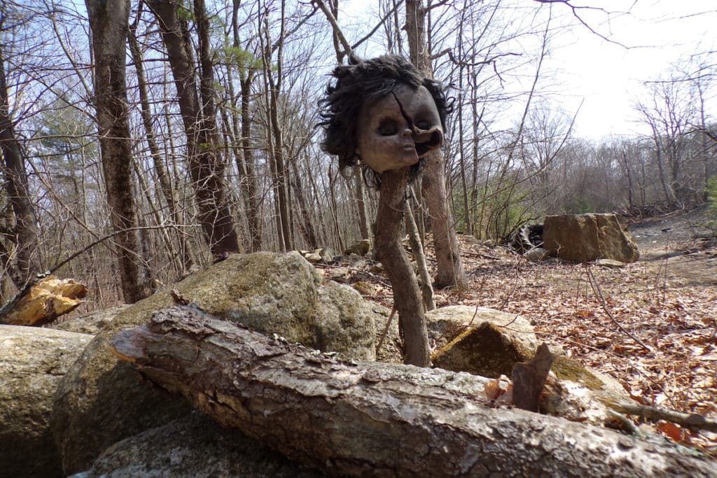 a burned doll head on a stick on the trail
